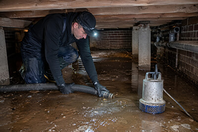 servicemedewerker die een kruipruimte aan het leegpompen is